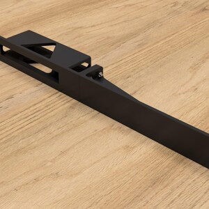 May include: A black metal bracket with a rectangular body and a triangular cutout. The bracket has multiple holes for mounting and a long, angled extension. The object is designed for structural support.
