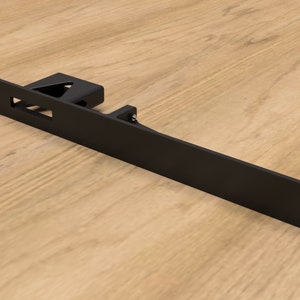 May include: Black metal bracket with a rectangular shape and a small rectangular cutout. The bracket has several holes for mounting.