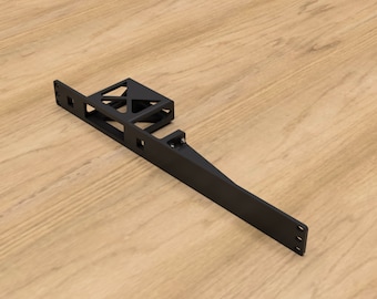 May include: Black metal bracket with a rectangular shape and a small, open, rectangular box on the top. The bracket has several holes for mounting.