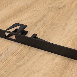 Peut inclure: Un support métallique noir avec une base rectangulaire et des pièces de support inclinées. Le support comporte plusieurs trous pré-percés pour le montage. L'objet est conçu pour le support structurel et est probablement utilisé dans les meubles ou la construction.