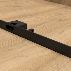 May include: A black metal rack mount component with a rectangular shape and a central cutout. The component has three holes on one end and a mounting bracket. The item is designed for mounting equipment.