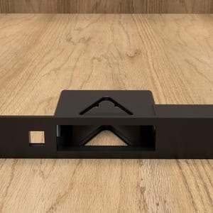 May include: A black metal bracket with a rectangular base and a square cutout. The bracket has a series of holes on one end and a triangular cutout on the top. The object is designed for mounting or support.
