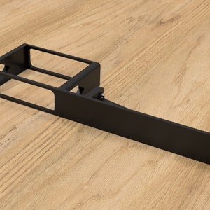 May include: Black metal shelf bracket with a rectangular opening and a long, flat extension. The bracket is designed to be mounted to a wall or other surface.