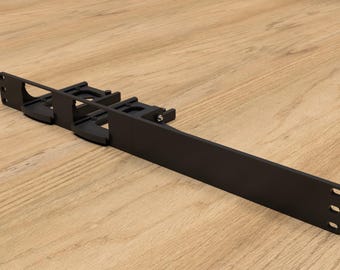 May include: Black metal rack with multiple slots for organising cables or wires. The rack is designed to be mounted on a wall or surface.