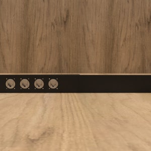 Peut inclure: Un rack en métal noir avec quatre ports RJ-45 pour les connexions réseau.