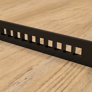 Puede incluir: Estante de plástico negro con 10 aberturas rectangulares. El estante está diseñado para sujetar cables o alambres.