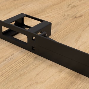 Può includere: Un rack in metallo nero con una lunga estensione orizzontale. Il rack ha più fori per il montaggio e un'apertura rettangolare al centro.