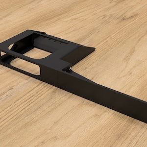 Op de afbeelding: Zwarte metalen beugel met een rechthoekige opening en een lange, vlakke verlenging. De beugel heeft meerdere gaten voor montage.