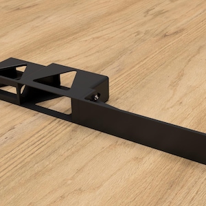 May include: Black metal bracket with a rectangular shape and multiple cutouts. The bracket has a long, flat section extending from the main body.