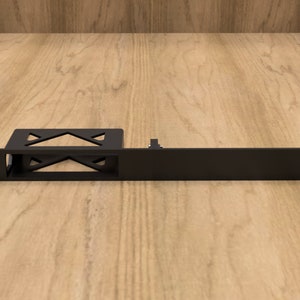 May include: A black metal rack mount shelf with a rectangular design. The shelf has a series of holes on the front edge and a bracket with an X-shaped design. The shelf is designed to hold electronic equipment.