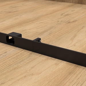 Peut inclure: Un loquet de porte en métal noir de forme rectangulaire. Le loquet comporte une ouverture centrale et est monté sur une surface en bois. Le loquet comporte trois trous à chaque extrémité.