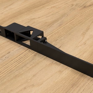 May include: Black metal bracket with multiple cutouts and holes. The bracket is long and narrow, with a flat surface on one side and a series of angled cutouts on the other.