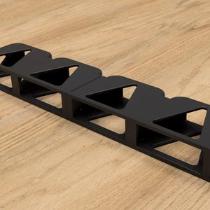 May include: Black metal shelf unit with five compartments, each shaped like a triangle. The shelf is designed to hold items like books or other decorative objects.