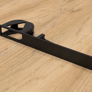 Könnte beinhalten: Schwarze Metallhalterung mit einem runden Ausschnitt und einer rechteckigen Öffnung. Die Halterung hat eine Reihe von Löchern entlang der Kante.