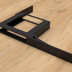 Puede incluir: Soporte de estante de metal negro con una abertura rectangular y un brazo largo y recto que se extiende desde el lateral. El soporte está diseñado para montarse en una pared u otra superficie.