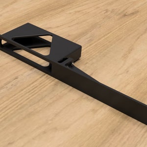 Pode incluir: Suporte de metal preto com uma abertura retangular e um braço longo que se estende para a direita. O suporte tem vários furos para montagem.