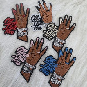 Puede incluir: Parches bordados con una mano marrón con uñas largas y cuidadas en rojo, negro, rosa y azul. Cada parche incluye un reloj plateado y el texto "Clock That Tea" en varios colores.
