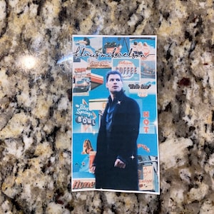 Op de afbeelding: Een collage van afbeeldingen met een man in een zwart jack en een blauw overhemd, met de tekst "Klaus Mikaelson" en "Hello love" op de achtergrond. De collage heeft een vintage esthetiek met een blauw en oranje kleurenschema.