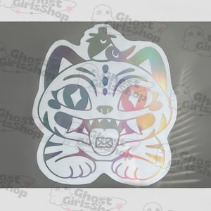 May include: A holographic sticker featuring a stylized cat with an open mouth and a tongue sticking out. The cat has a rainbow-colored design with a white outline and a small envelope graphic on its tongue.