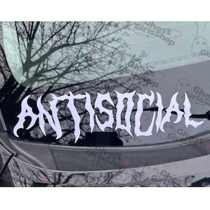 May include: White vinyl decal with the word "ANTISOCIAL" in a gothic font. The decal is displayed on a car window, with a blurred background of tree branches and a cloudy sky.