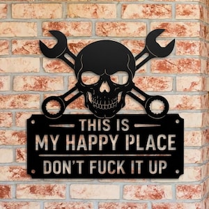 Puede incluir: Un letrero de pared de metal negro con una calavera centrada sobre dos llaves inglesas cruzadas. Debajo de la calavera, una placa rectangular muestra el texto: THIS IS MY HAPPY PLACE DON'T FUCK IT UP. El letrero tiene cuatro pequeños orificios.
