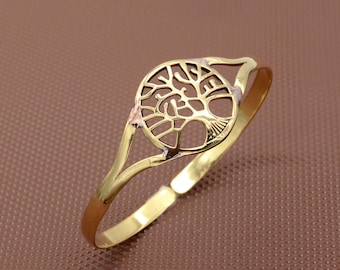 May include: A gold-toned bangle bracelet with a tree of life design. The bracelet is open and adjustable.