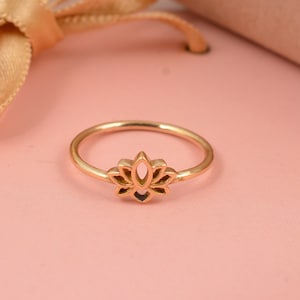 Op de afbeelding: Een ring van goudkleurig metaal met een lotusbloem ontwerp. De ring is delicaat en heeft een eenvoudige, elegante stijl.