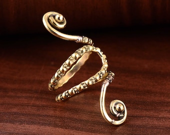 Op de afbeelding: Een ring van goudkleurig metaal met een uniek, gedraaid ontwerp. De ring heeft een getextureerde band met een spiraaldetail aan elk uiteinde.