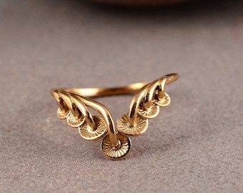 May include: A gold-colored ring with a unique design. The ring features a series of small, circular elements connected by curved lines, creating a delicate and artistic appearance. The ring is set against a neutral background, highlighting its intricate details.