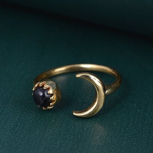 Peut inclure: Bague en or avec un motif de croissant de lune et une pierre précieuse noire. La bague est ouverte d'un côté.