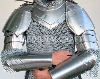 May include: A silver chainmail shirt with matching silver shoulder and elbow armor. The armor is worn by a person with a beard and a silver chainmail coif.