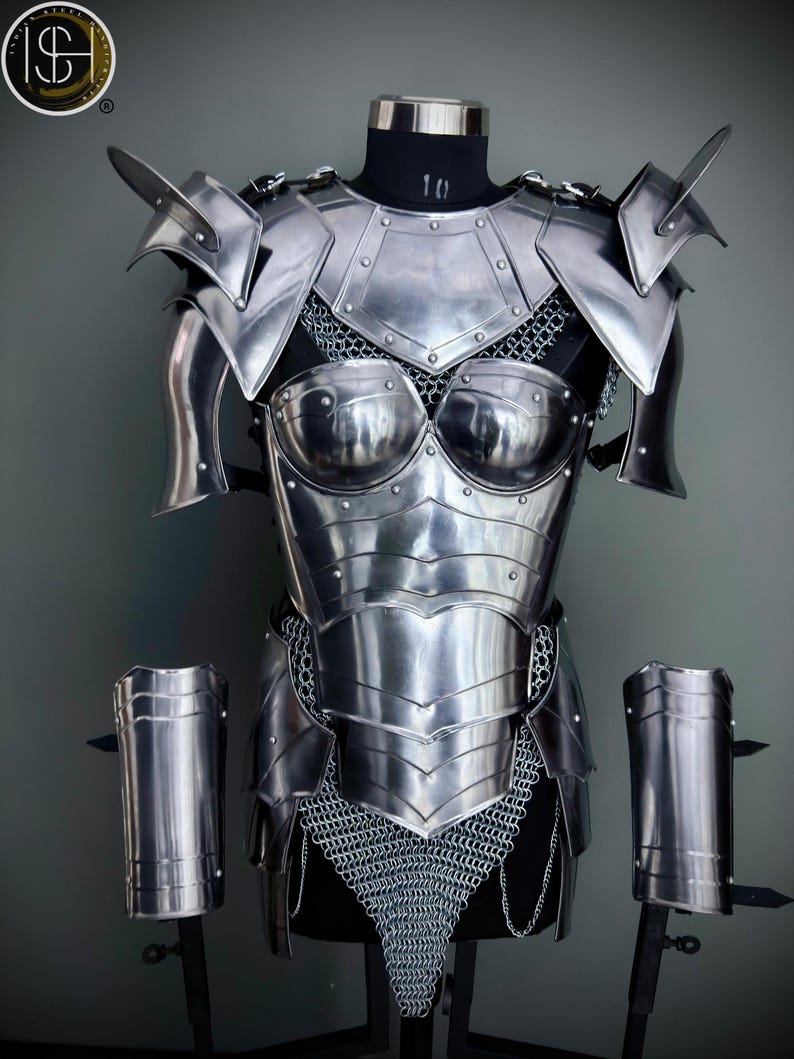 Peut inclure: Une armure en m&eacute;tal argent&eacute; avec une jupe en cotte de mailles et des prot&egrave;ge-bras assortis. L'armure est expos&eacute;e sur un mannequin.