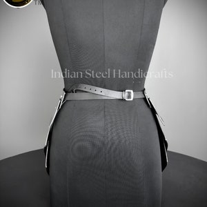 May include: Black leather belt with silver buckles and a silver chain detail. The belt is worn on a black dress form. The text "Indian Steel Handicrafts" is visible on the dress form.