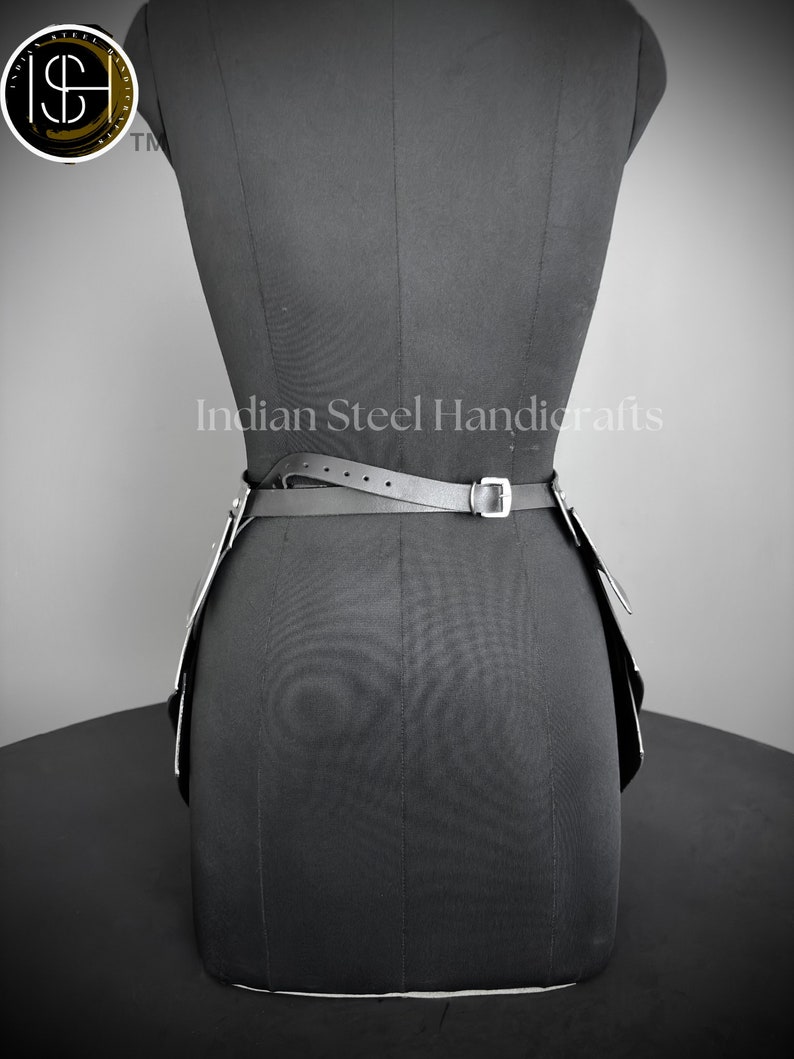May include: Black leather belt with silver buckles and a silver chain detail. The belt is worn on a black dress form. The text "Indian Steel Handicrafts" is visible on the dress form.