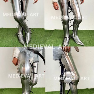 May include: A pair of silver-colored medieval leg armor with knee pads and pointed toe coverings. The armor is made of metal and has a shiny finish.
