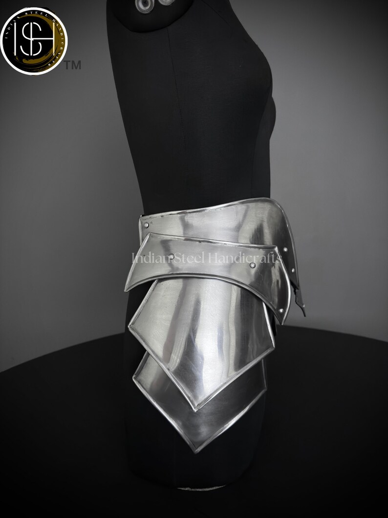 May include: Silver metal armor for the waist and hips, with a series of overlapping plates. The armor is displayed on a black mannequin.