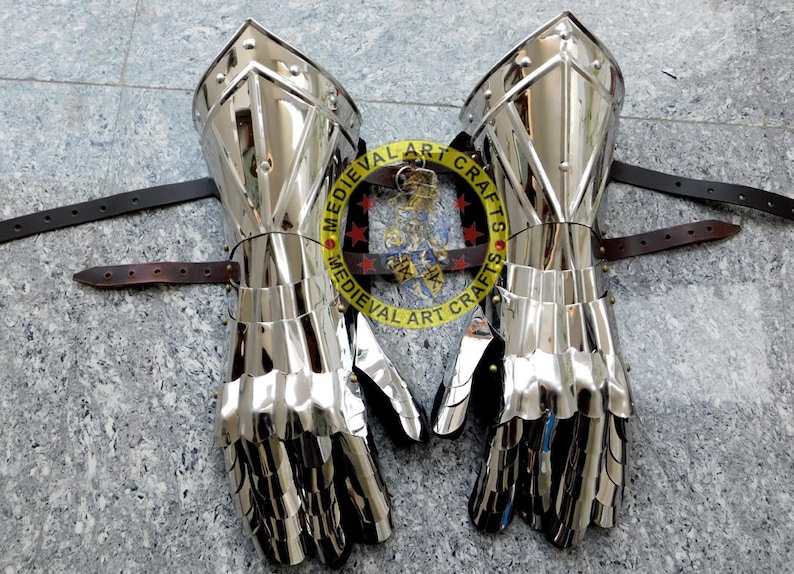 May include: A pair of silver plated medieval gauntlets with leather straps. The gauntlets are made of metal plates and have a pointed design. The gauntlets are for the left and right hand.