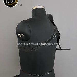 May include: Black leather shoulder armour with metal accents and straps. The armour is worn on a black mannequin. The text "Indian Steel Handicrafts" is visible on the mannequin.