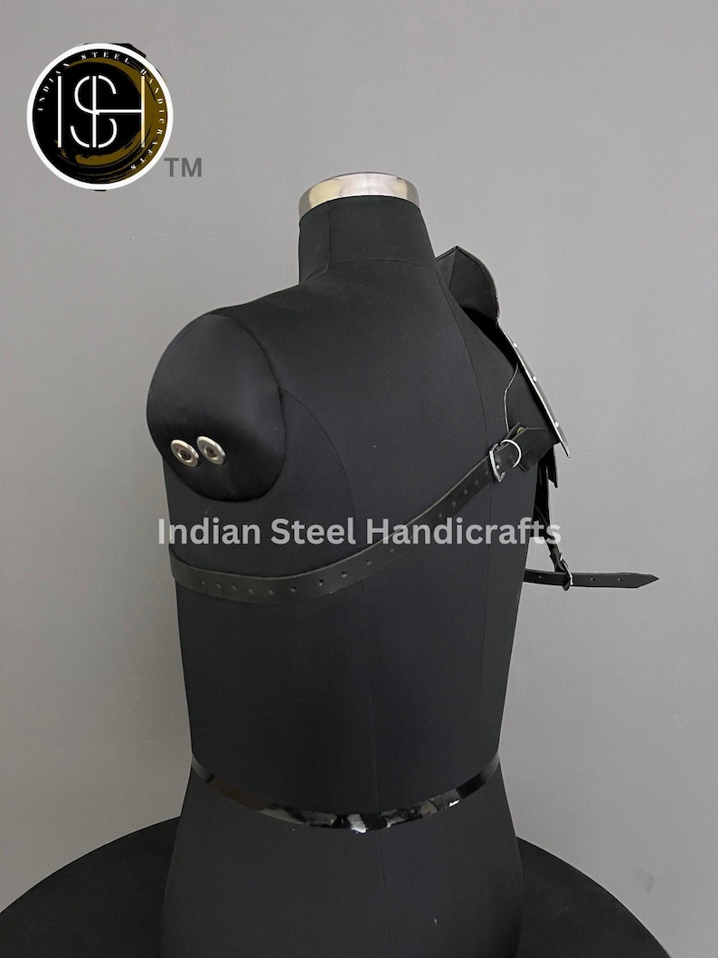 May include: Black leather shoulder armour with metal accents and straps. The armour is worn on a black mannequin. The text "Indian Steel Handicrafts" is visible on the mannequin.