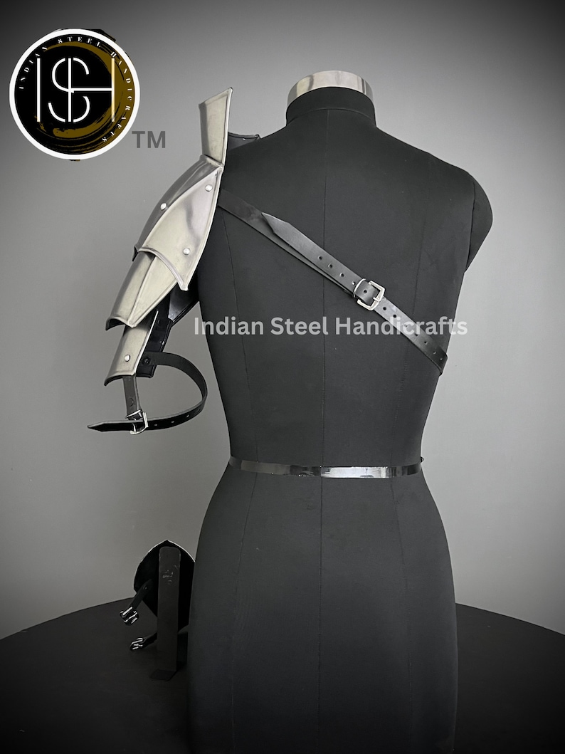 K&ouml;nnte beinhalten: Eine silberne Schulterr&uuml;stung aus Metall mit Riemen und Schnallen. Die R&uuml;stung wird von einem schwarzen Mannequin getragen. Der Text "Indian Steel Handcrafts" ist auf dem Mannequin sichtbar.