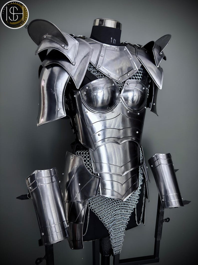 Peut inclure: Une armure en m&eacute;tal argent&eacute; avec une jupe en cotte de mailles et des prot&egrave;ge-bras assortis. L'armure est expos&eacute;e sur un mannequin.