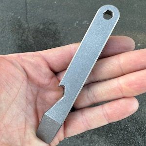 May include: A silver metal pry bar tool with a bottle opener and a hex wrench.