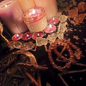 May include: A close-up of a crystal grid with candles and a beaded bracelet. The crystals are clear and the candles are pink and white. The bracelet is made of brown beads.