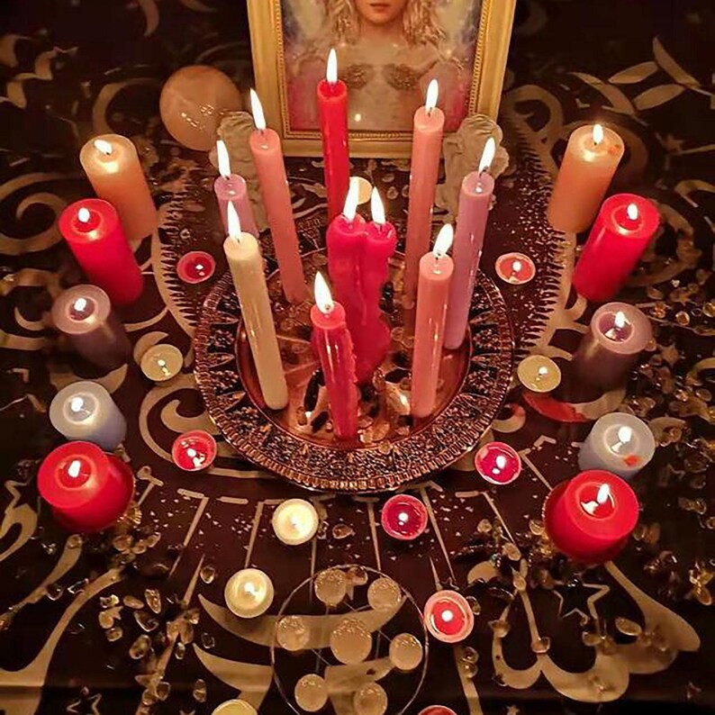 Pu&ograve; includere: Primo piano di un tavolo con una variet&agrave; di candele disposte in cerchio. Le candele sono di diversi colori, tra cui rosso, rosa, bianco e viola. Ci sono anche diversi piccoli oggetti rotondi sparsi intorno alle candele.