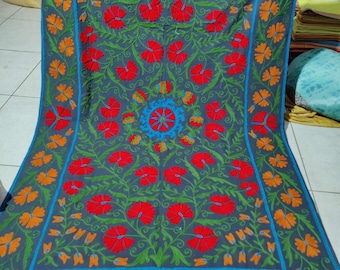 May include: A grey cotton throw blanket with a floral embroidery design. The embroidery features red, orange, and green flowers on a dark grey background. The blanket has a blue border.