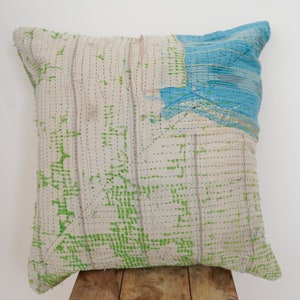May include: A white, blue, and green patchwork pillow with a geometric pattern. The pillow is made of recycled fabric and has a unique, handmade look.