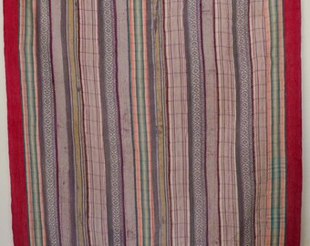 May include: A rectangular, vertically striped textile with a red border. The stripes are in shades of gray, pink, green, and yellow. The border is a solid red. The textile appears to be handmade.