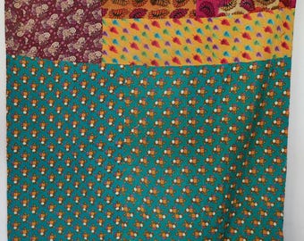 May include: A rectangular quilt featuring a patchwork design with various fabric patterns. The top section displays blocks of purple, orange, and pink floral and leaf prints, while the large bottom section is a teal fabric with small floral motifs.