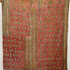 Peut inclure: Textile vintage rouge avec un motif géométrique répété vert et crème. Les bords présentent une bordure détaillée. Le textile a un aspect usé et antique, suggérant qu'il s'agit d'une pièce ancienne.