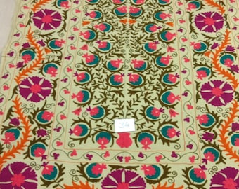 May include: A cream-colored fabric with a floral embroidery design. The embroidery features pink, orange, green, and teal flowers and leaves. The number "34" is written in black on the fabric.